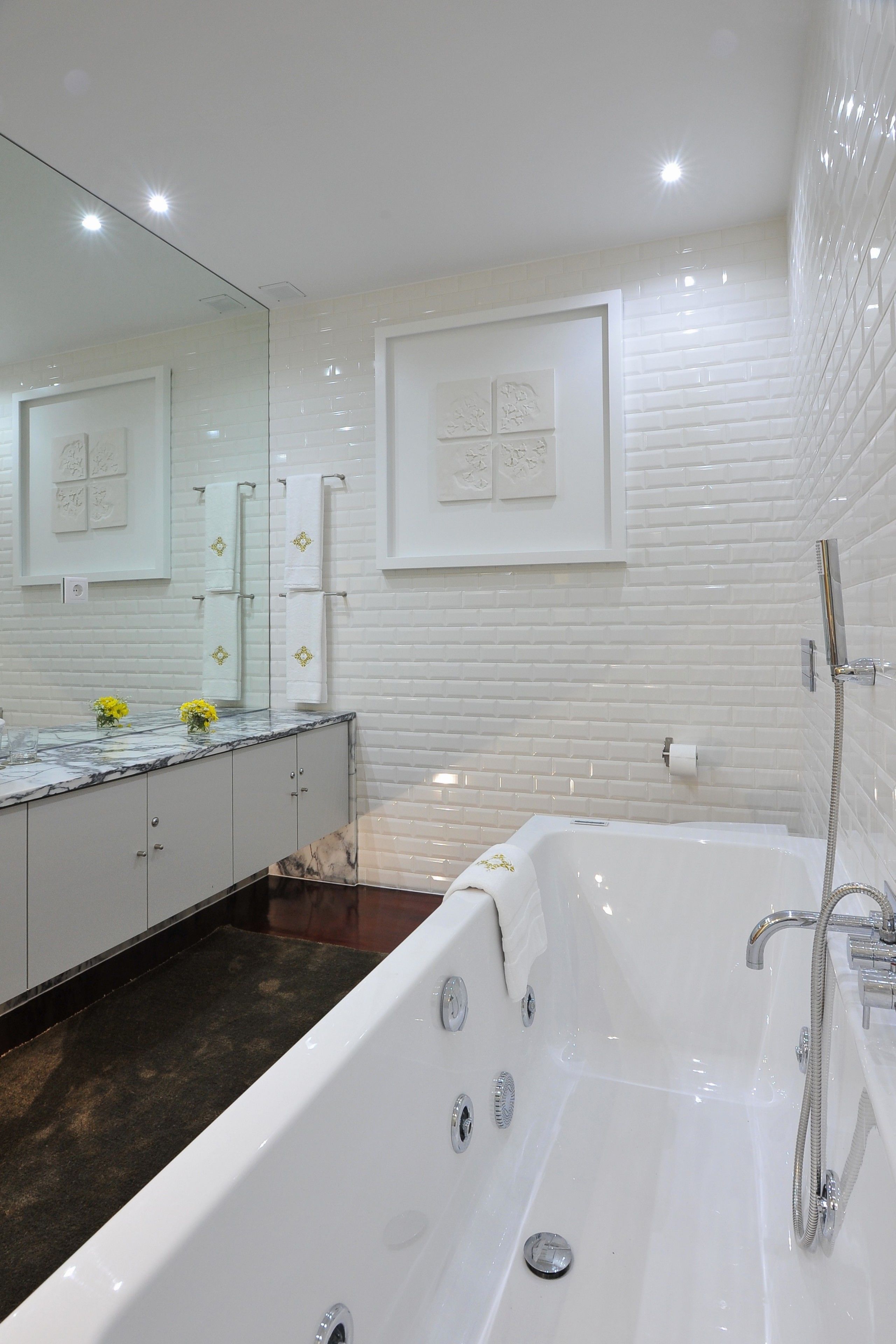 Une salle de bain moderne avec une grande baignoire, un meuble-lavabo avec un miroir et des murs recouverts de carreaux blancs.