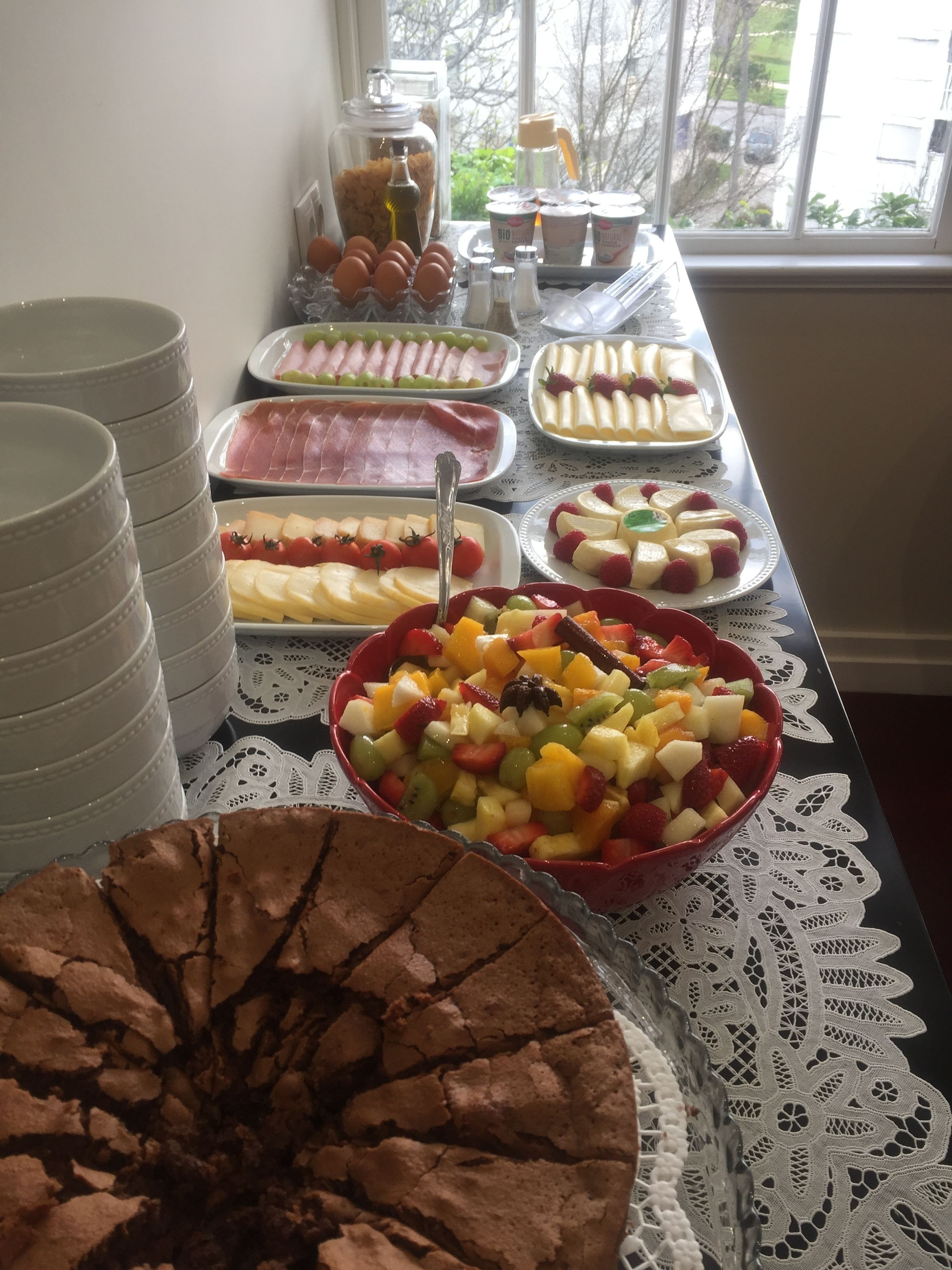 A buffet table with various food items including fruits, cheeses, and meats.