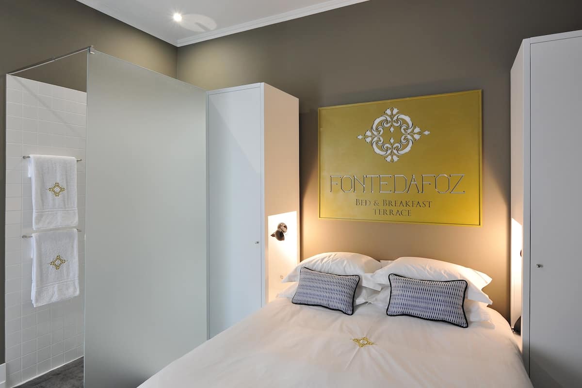 A hotel room with a bed, a shower, and a wall-mounted sign.