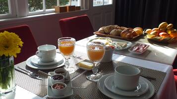 A breakfast table with various food items, drinks, and utensils.