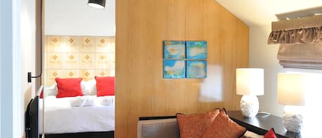 A hotel room with a bed, a sofa, a lamp, and a painting on the wall.