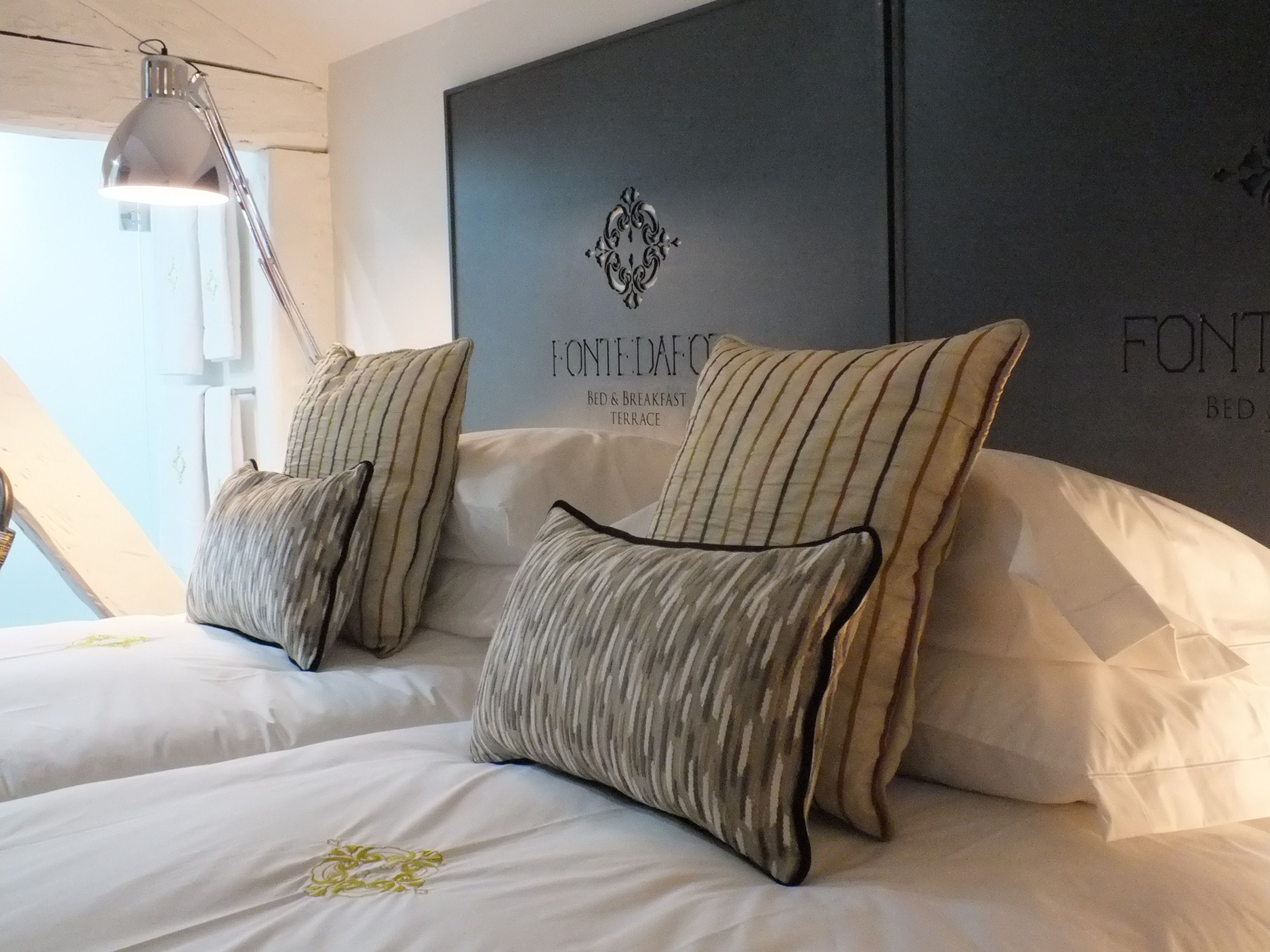 Una camera da letto con due letti, cuscini a righe e un lampadario a parete.