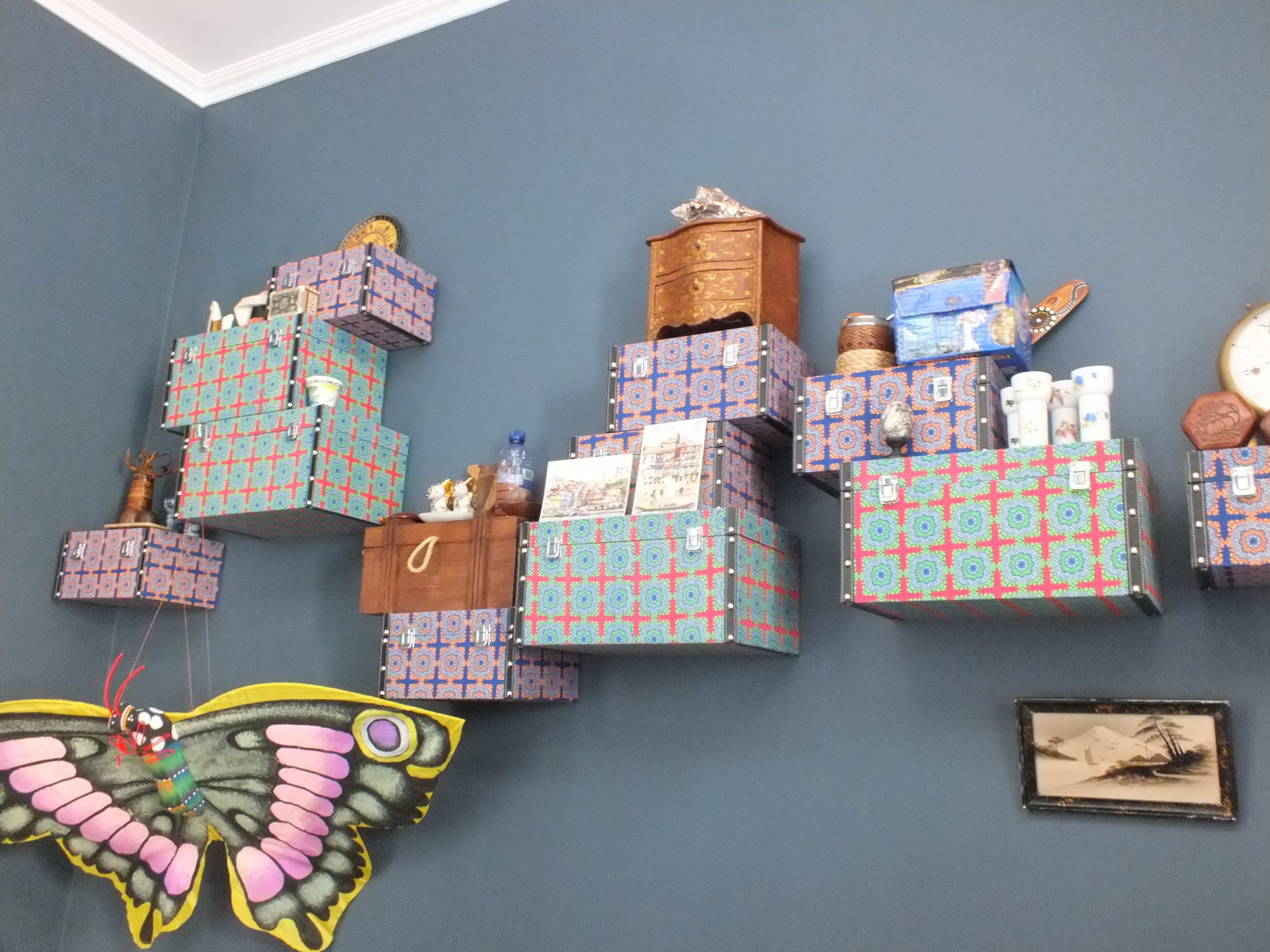 Un mur orné de boîtes de différentes tailles, dont certaines présentent des motifs, et d’une décoration en forme de papillon.