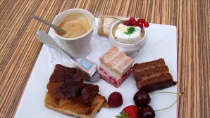 Um prato com diversas sobremesas, incluindo uma fatia de torta, um sanduíche e uma xícara de café.
