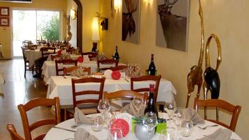 A restaurant with round tables set for dining, wooden chairs, and wine glasses.