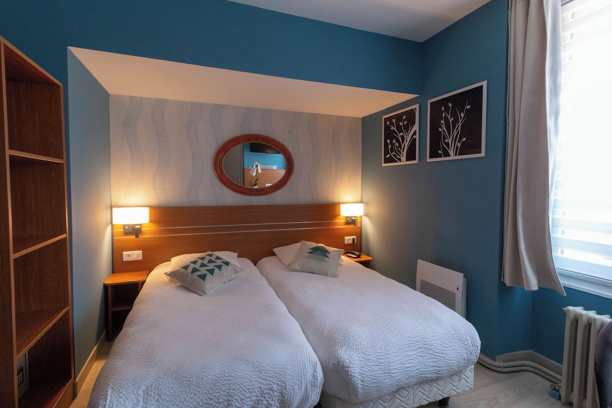 Una habitación de hotel con dos camas, un cabecero de madera, un espejo redondo y decoración en la pared.