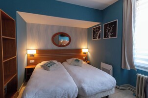 Una habitación de hotel con dos camas, un cabecero de madera, un espejo redondo y decoración en la pared.