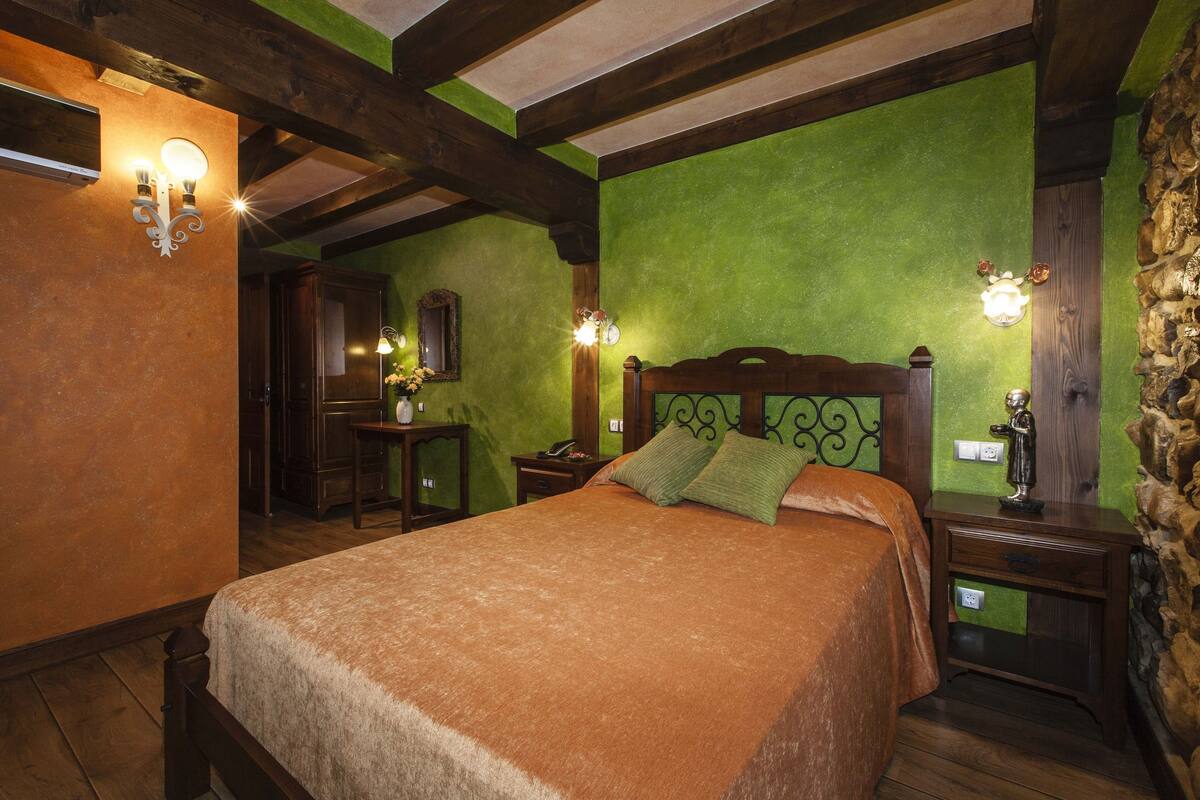 Ein Schlafzimmer mit einem großen Bett, einem Holz-Kopfteil, grünen Wänden und einer Wand als Steinakzent.