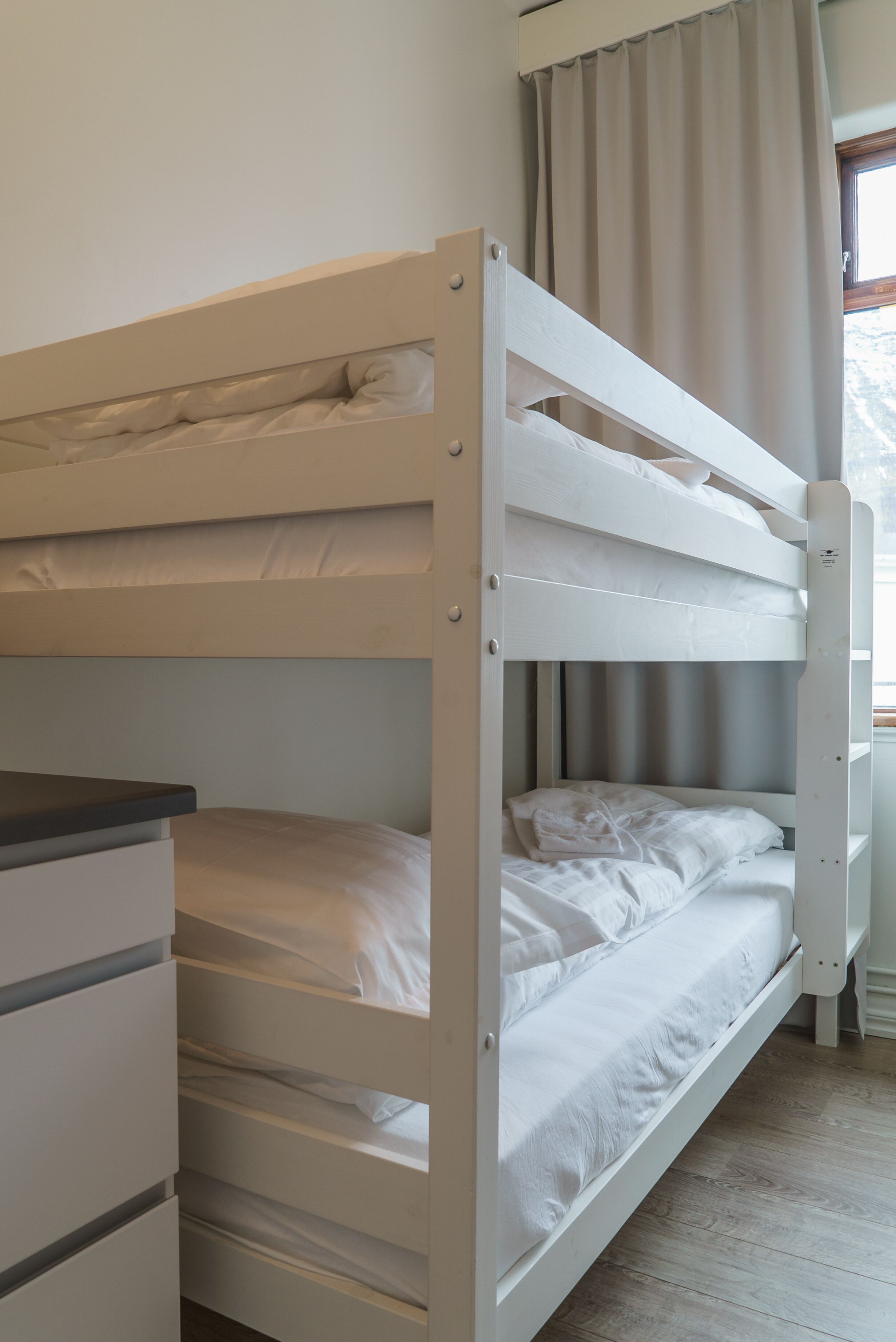A bunk bed with white bedding and a wooden headboard.