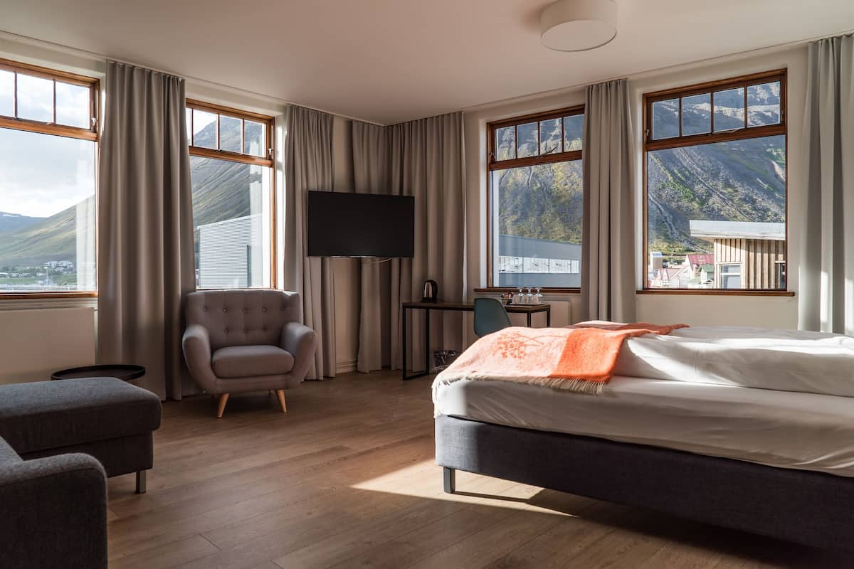 A hotel room with a bed, a desk, a chair, and a TV.