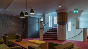 Un hall d’entrée moderne avec un escalier, un espace salon et un mur orné de motifs.