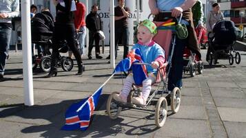 A public square with people walking, a child in a stroller, and a flag on the ground.