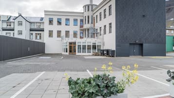Un hôtel moderne doté d’une entrée centrale, d’un espace extérieur couvert aménagé en coin salon et d’un parking.