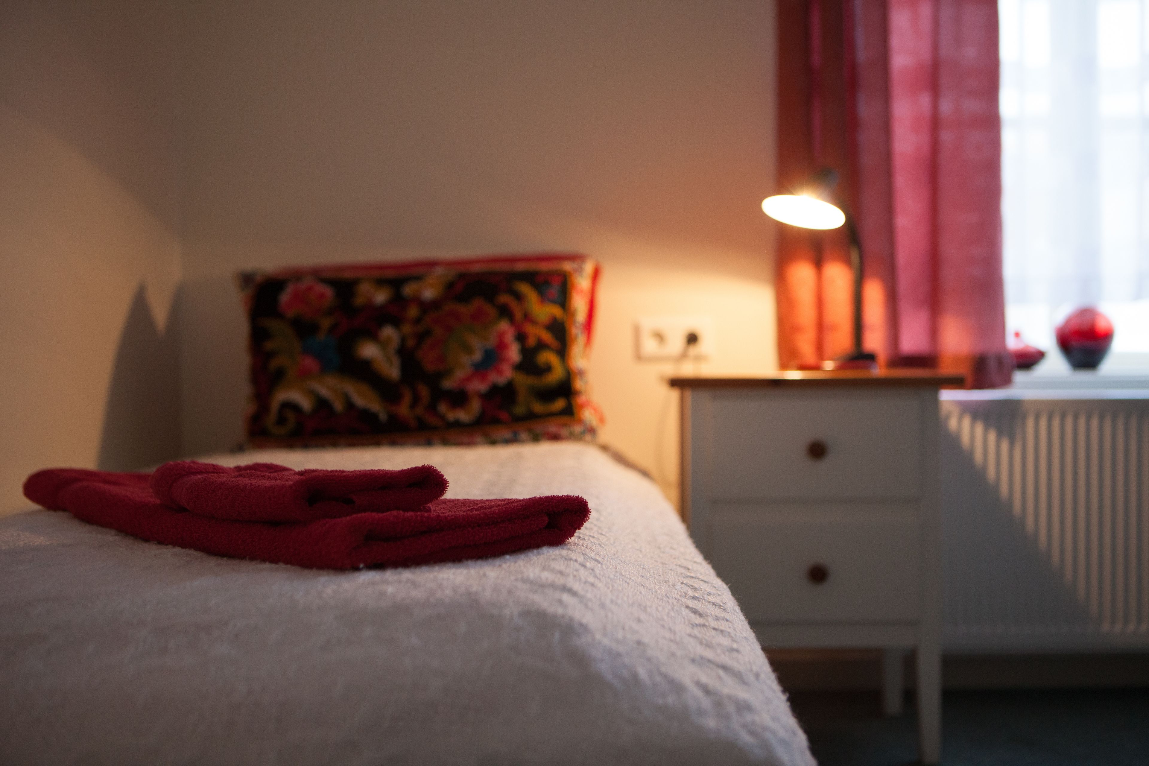 A neatly made bed with a white sheet and a folded red towel.