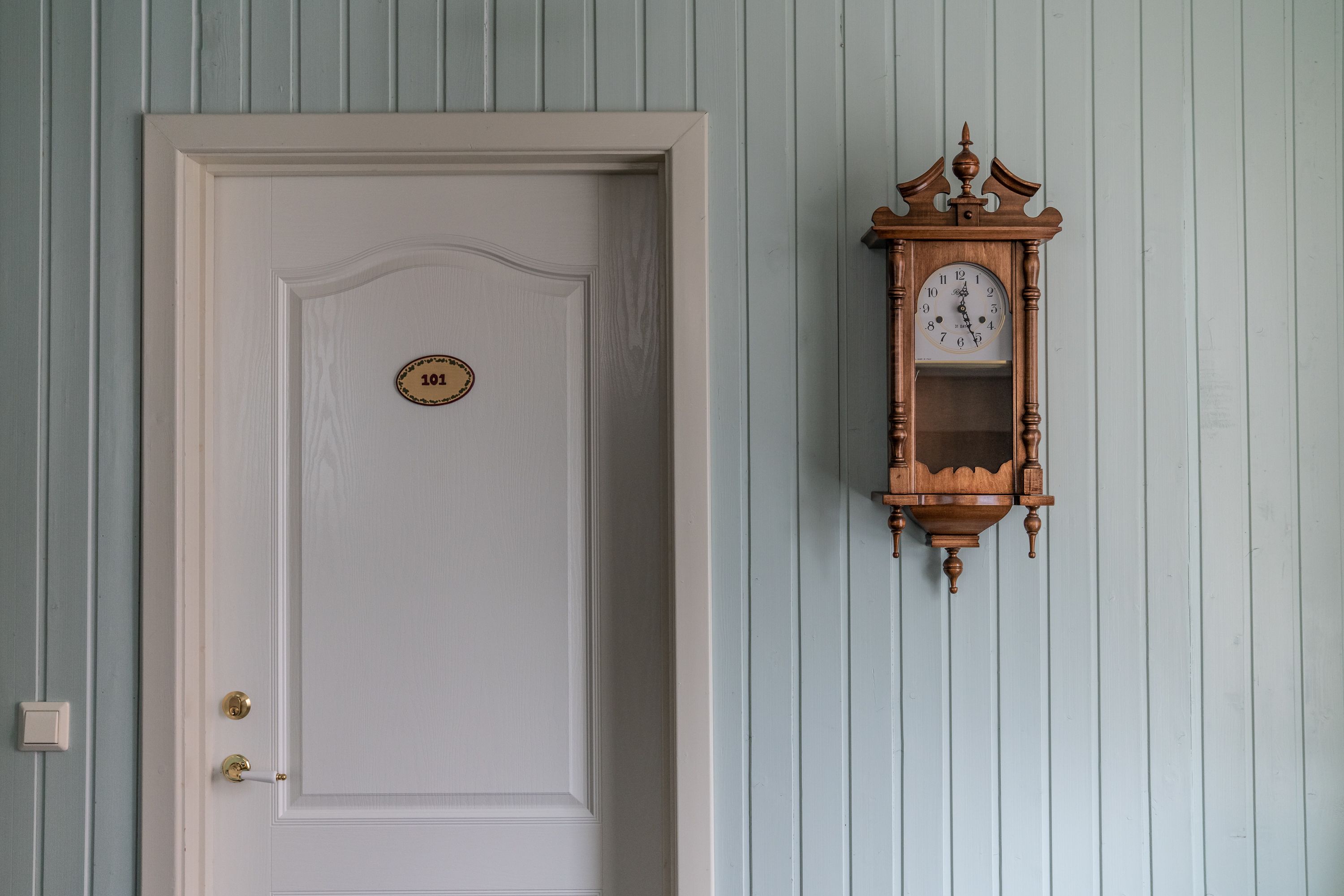 A white door with a brass doorknob and a brass plate with the number 101.