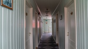 Un pasillo de hotel con alfombra a cuadros, puertas blancas y un ventilador de techo.