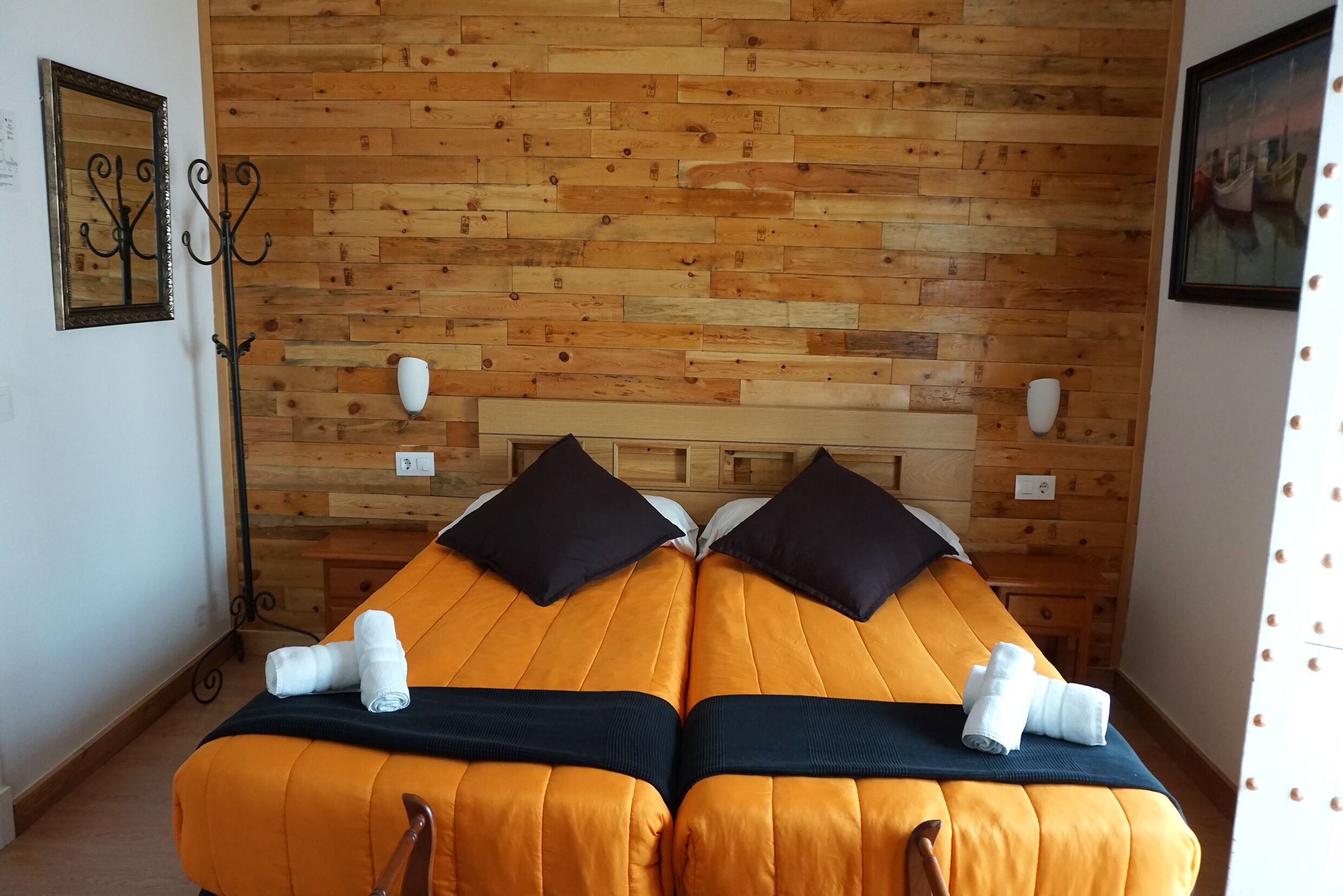 A room with two beds, wooden wall paneling, and a simple, functional design.