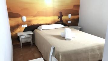 Una habitación de hotel con una cama, una mesita de noche y un mural en la pared que representa un paisaje tranquilo.