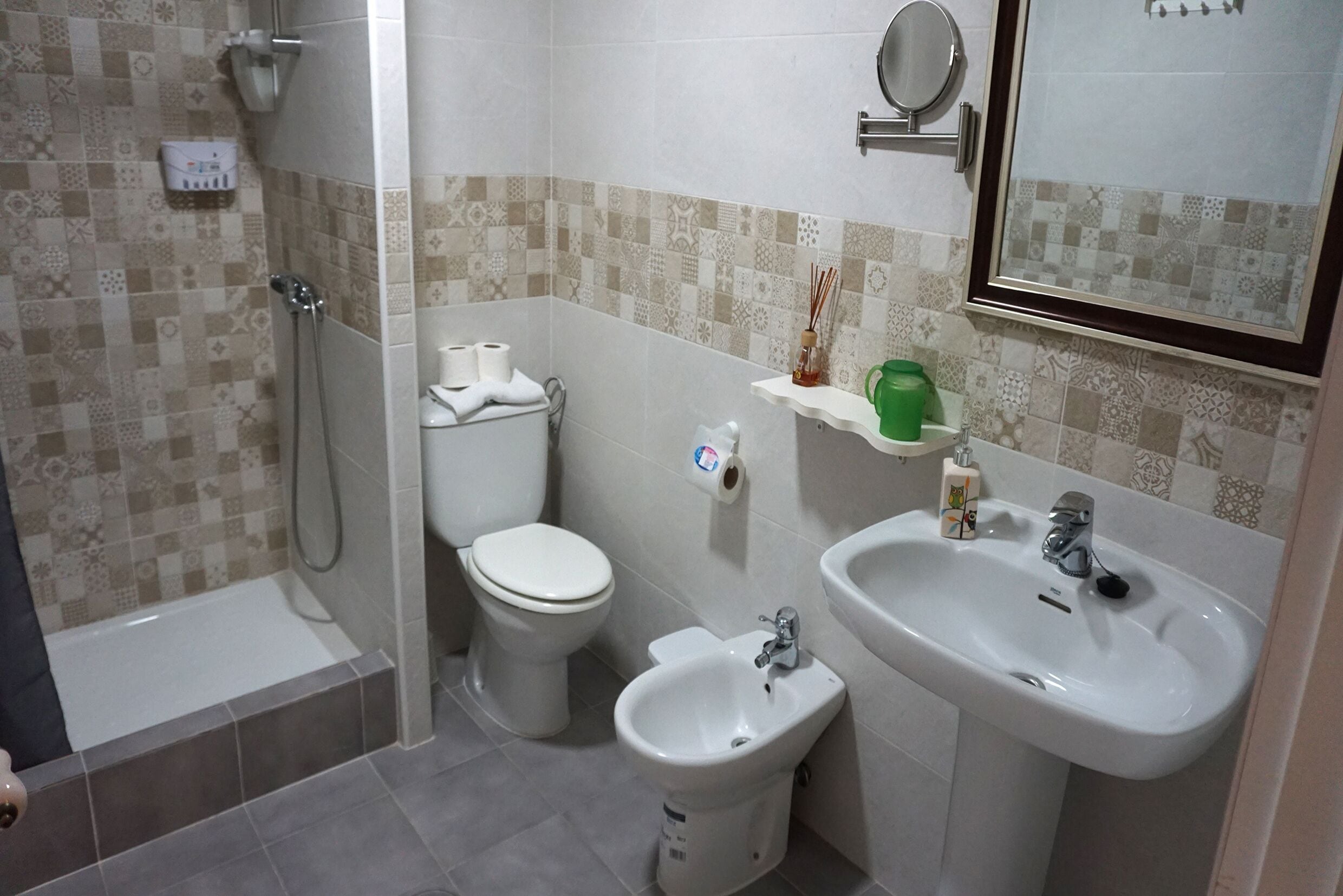 A bathroom with a bathtub, toilet, bidet, sink, and a mirror.