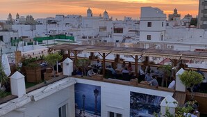 Une terrasse sur le toit, aménagée avec des espaces pour s’asseoir, offrant une vue sur le paysage urbain au coucher du soleil.