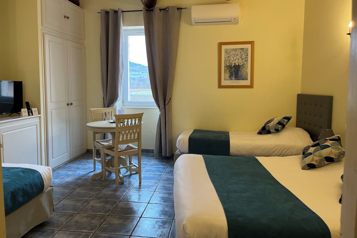 Een kamer met twee bedden, een bureau met stoel, een televisie en een airconditioner.