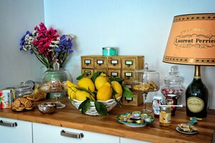 A kitchen counter with various food items, a bottle of champagne, and a decorative lamp.