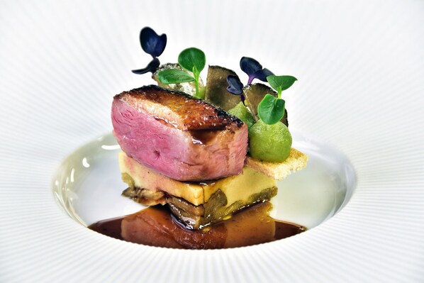 A plated dish with a slice of meat, vegetables, and a sauce.