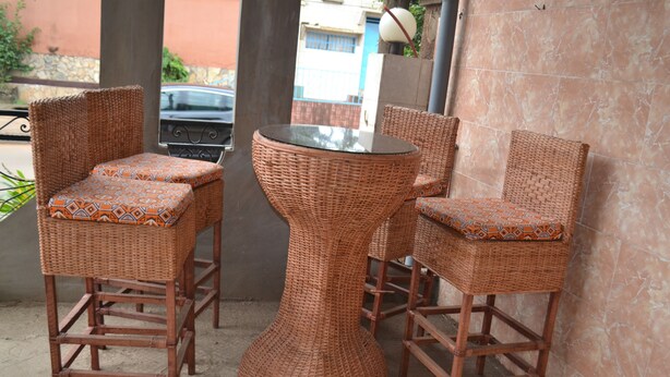 A wicker table and chairs set outdoors with a tiled wall in the background. - Hotel Le Diplomate (Yaoundé)