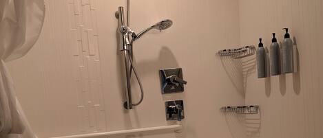 A bathroom with a shower, toilet, and handrails.