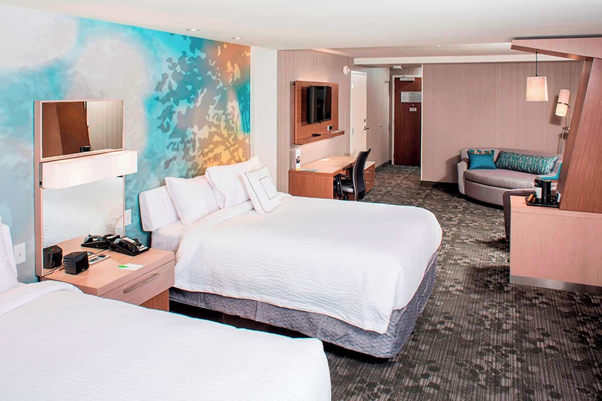Une chambre d’hôtel avec deux lits, un bureau, une télévision et un canapé.