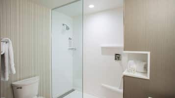 Un baño moderno con ducha de vidrio, inodoro y tocador con barra para toallas.