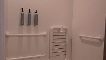 Ett badrum med badkar, stödhandtag och tre flaskor handsprit.