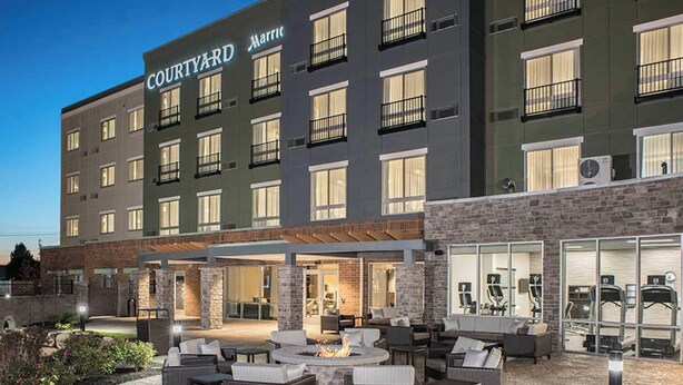 A Courtyard Marriott hotel with outdoor seating, a fire pit, and a fitness center visible through the glass doors. - Courtyard by Marriott Albany Clifton Park (Clifton Park)
