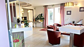 En hotellobby med en receptionsdisk, en sittgrupp och en stor spegel.