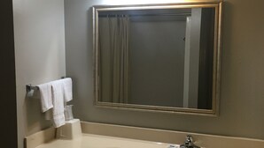 A bathroom with a large mirror, a sink, and a towel rack. - Sunset Inn (West Memphis)