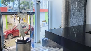 A modern lobby with a reception desk, a large mirror, and a view of the street outside. - Ayenda 1139 Castellón Plaza (Pereira)