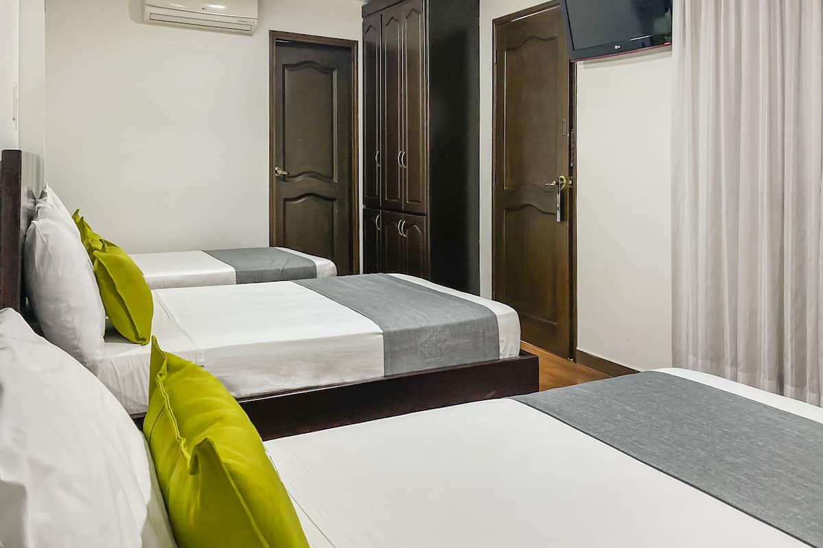 A hotel room with two beds, a wardrobe, a television, and a curtain.