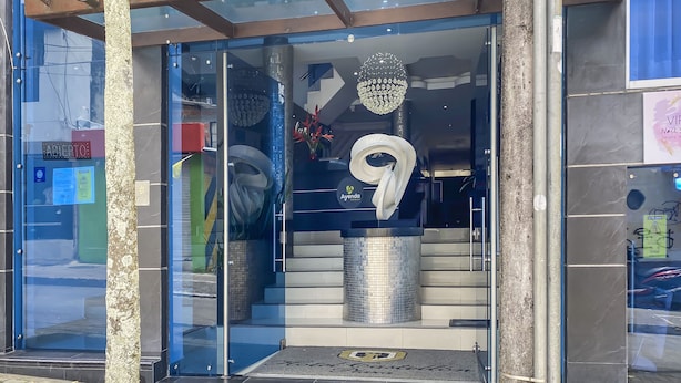 A modern building entrance with glass doors, a metal staircase, and a decorative hanging light fixture. - Ayenda 1139 Castellón Plaza (Pereira)