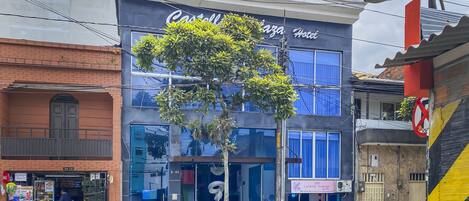 Um hotel com fachada de vidro ampla, uma escadaria visível e a placa "Castell Plaza Hotel".