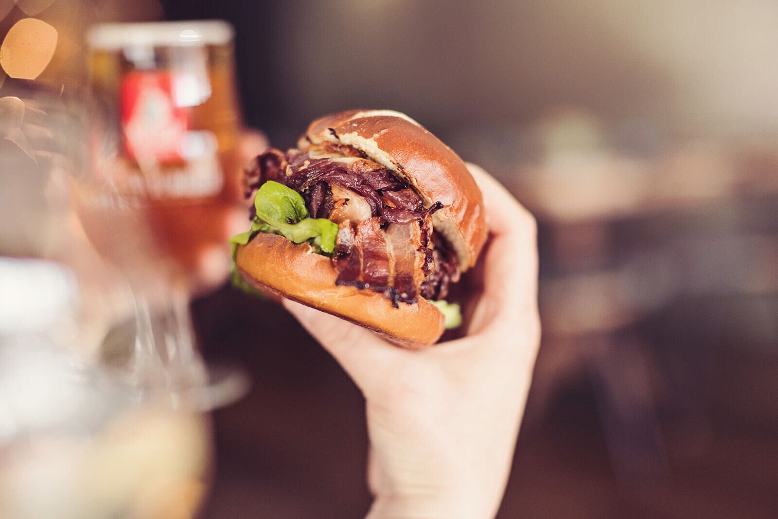 Een hand die een hamburger vasthoudt, met zichtbaar sla en een broodje.