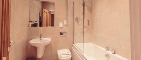 A modern bathroom with a large bathtub, a sink, and a toilet.