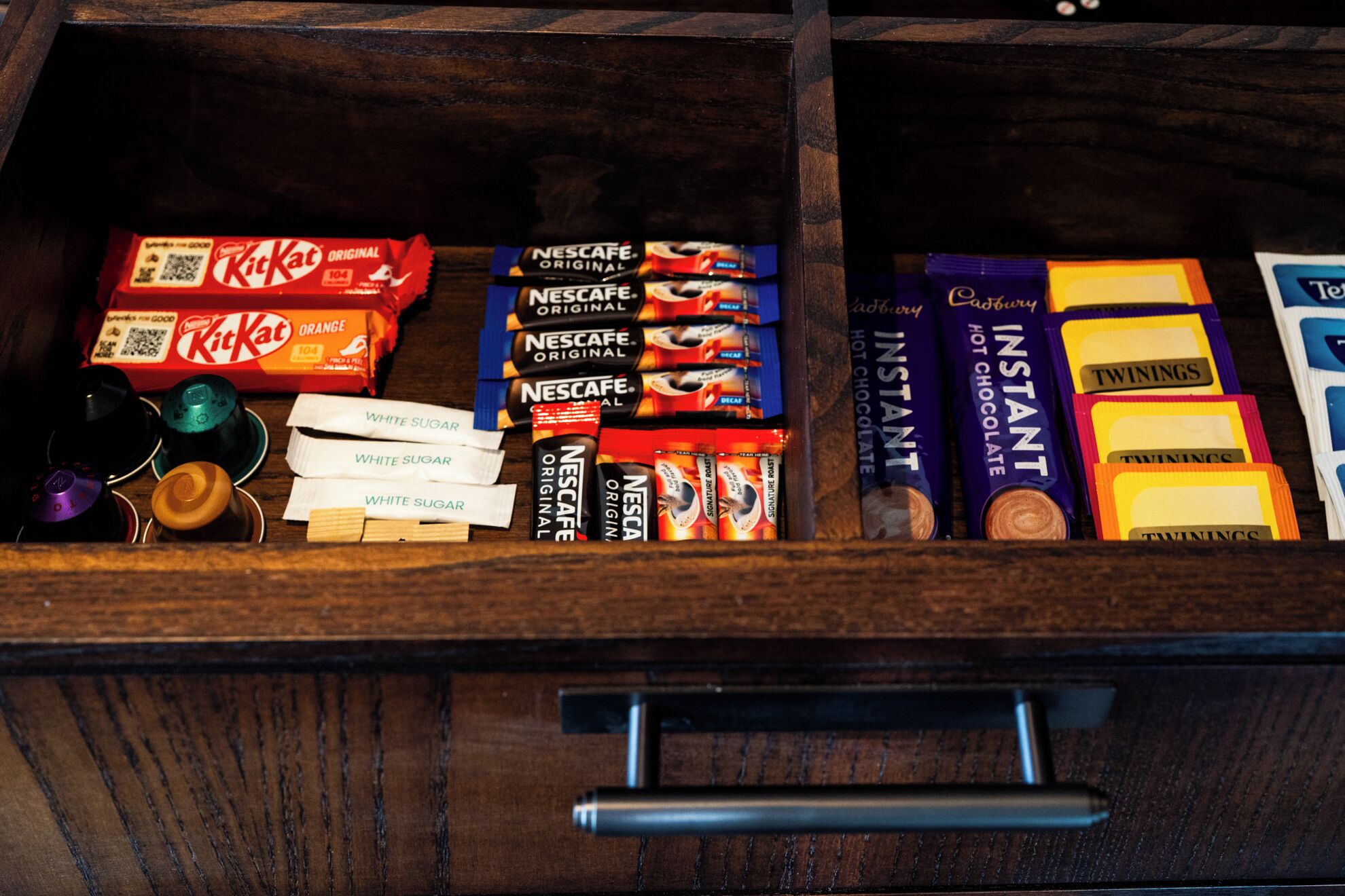 A drawer with various chocolate bars and instant coffee packs.