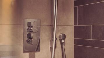 A shower with a wall-mounted control panel and a handheld showerhead.