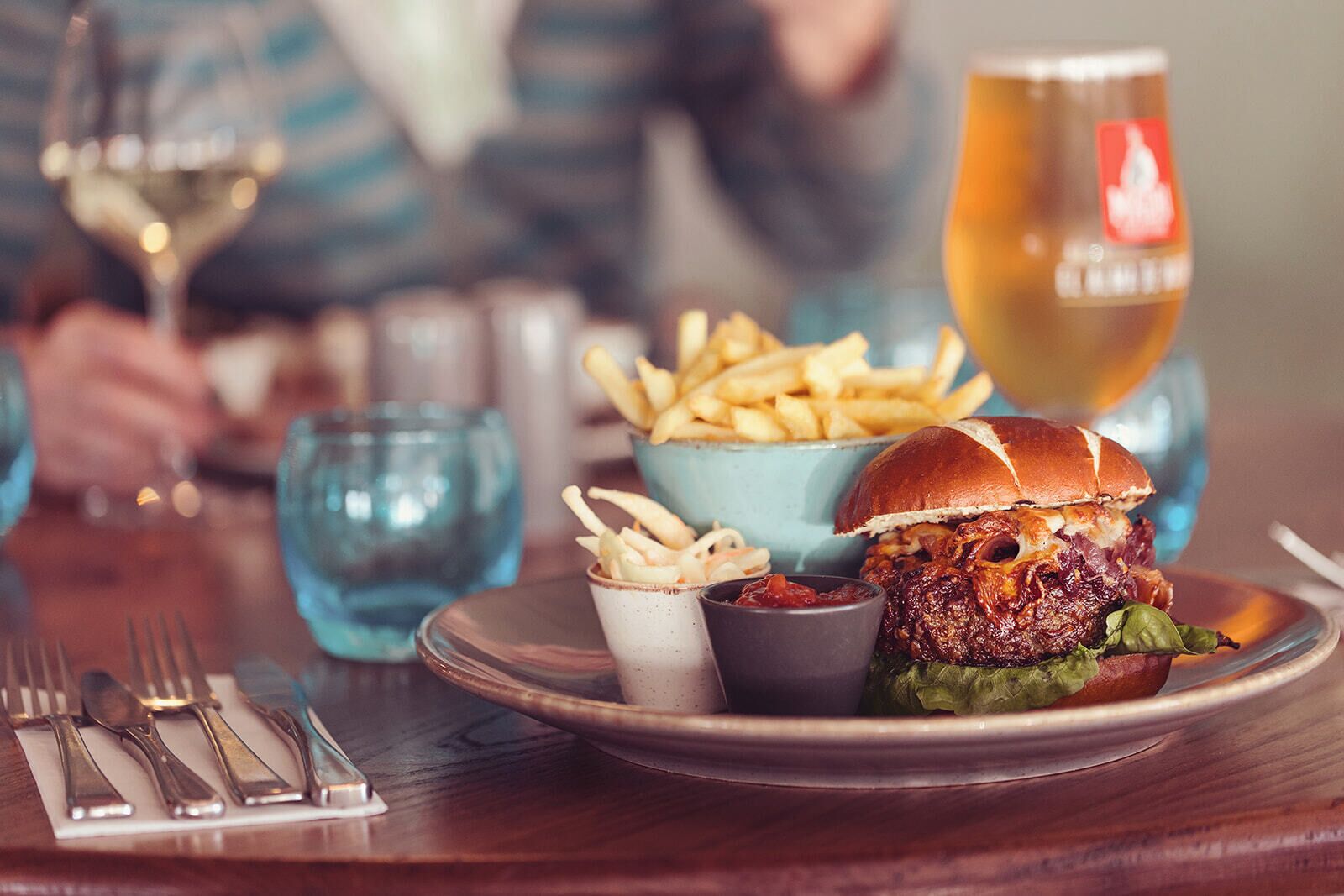 A meal with a burger, fries, and a drink on a table.