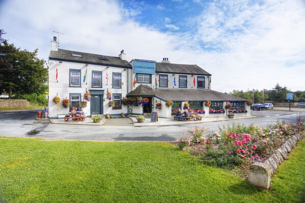 Un pub traditionnel avec une terrasse et des jardinières fleuries.