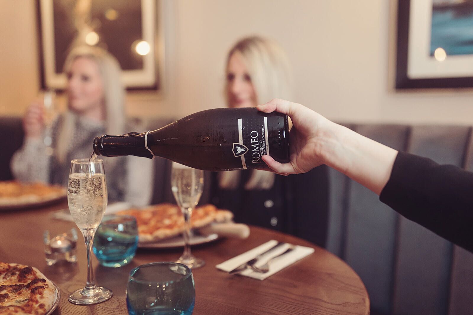 Eine Person gießt eine Flasche mit dem Aufdruck 'ROMEO' in ein Glas.