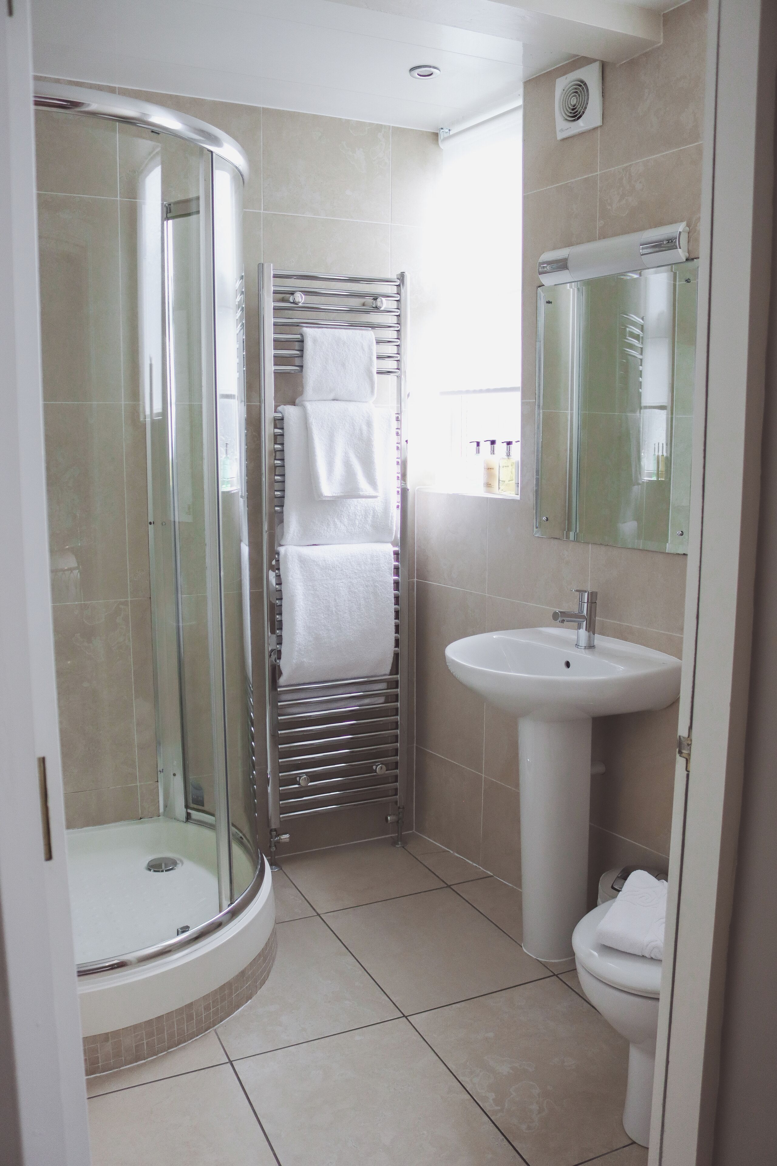 Un baño con ducha de vidrio, un lavamanos blanco y un inodoro.