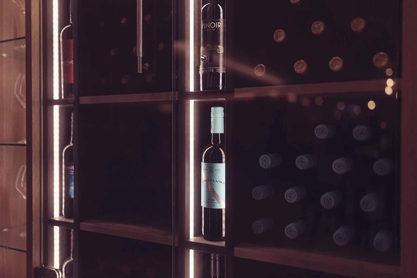 Un porte-bouteilles contenant des bouteilles, dont une étiquetée « VINOIR » et une autre étiquetée « DONDELUNA ».