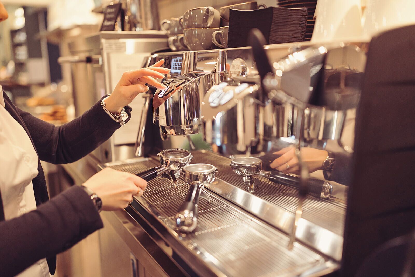 A barista preparing coffee using a professional espresso machine.