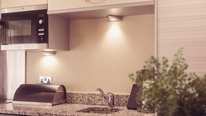 Una cocina moderna con microondas integrado, un lavamanos de acero inoxidable y encimera de granito.